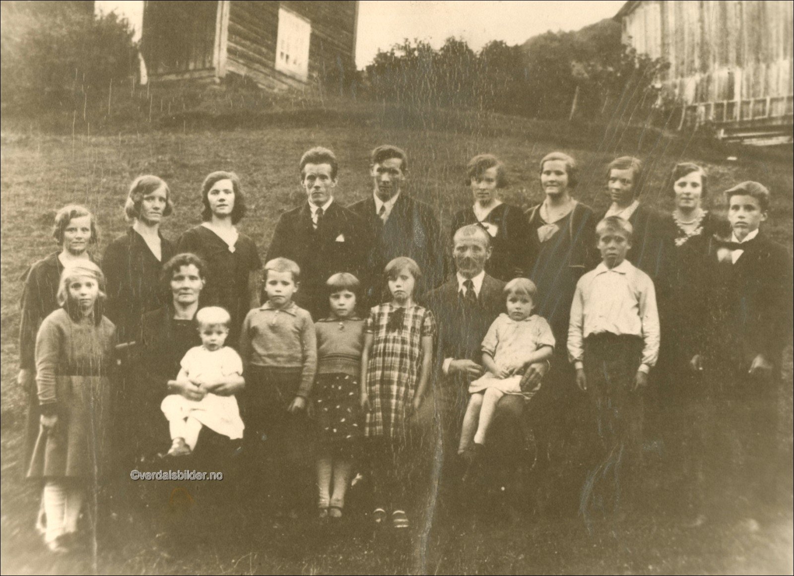 Her er foreldrene og 17 av de 18 søsken Vollan. Den yngste, Gunnar, var ikke født. Bildet er tatt på konfirmasjonsdagen til Ola. Noe av heimen i bakgrunnen. Utlånt av Paula Holmli.