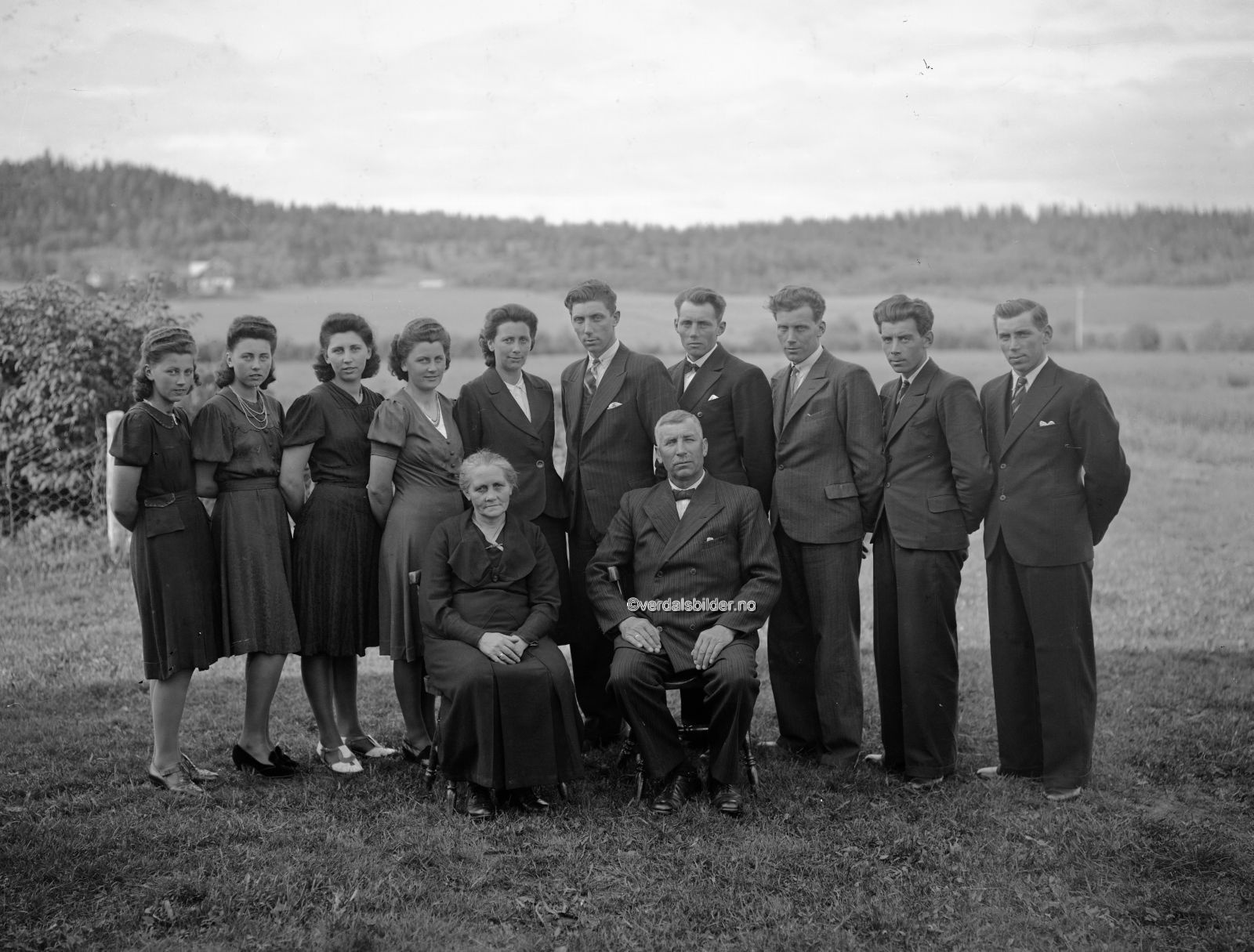 Benjamin Magnus Hansen (1879-1948) og Grethe Birgitte Bernhardusdatter (1880-1981)<br />
Benjamin Hansen startet opp med nybrottsarbeide på Forbregd søndre i 1904. Han kom opprinnelig fra Bjugn, og i tillegg til drifta av gården arbeidet han som anleggsarbeider.<br />
Han reiste mye omkring. 1 1900 finner vi han i et arbeidslag på jernbaneanlegget på Åsen. Han var også med arbeidet på Bergensbanen.<br />
Han var da ugift og bodde på gården Råa. Benjamin Hansen kjøpte en lærerbolig i Vinne og flyttet den til sin eiendom Forbregd søndre hvor den ble oppført som bolighus.<br />
Han var senere i Folla, der han og to sønner arbeidet med bygging av kaia. De hadde dykkerutsyr med drakt, hjelm,&nbsp; luftslange og blysko!<br />
Han arbeidet også med byggingen av festningene i Sogna (sprengingsbas) og eneste fremkomstmidlet dit var føttene, så det ble mange kilometers gange til og fra arbeidet.<br />
Han ver også med i kommunestyret. Og han var målmann i fotballaget Falk! Vassledningen mellom Leklemsvatnet og Øra var også en av hans arbeidsplasser. Han dreiv også som murer og betongarbeider,<br />
og der var også noen av hans sønner med på arbeidslaget.&nbsp; (Mære landbruksskole). Benjamin, Harald og Erling var med restaureringsarbeide ved Stiklestad kirke (1927-30).<br />
De grov bl.a. en dreneringsgrøft fra kirkegårdsmuren til Korsådalsbekken (150 m). På det dypeste var grøfta 5,30 under bakkenivå! I dreneringsgrøfta ble det lagt 12 tommers sementrør.<br />
Benjamen ble født i Bjugn, sønn av Hans og Ellen Jelgalid. Han ble gift i 1903 med Grethe Birgitte Bernhardusdatter.<br />
Grete var født på Fleskhusvald, og hun var datter av Bernhardus Johannesen og Gurianna Larsdatter. Benjamin og Grethe hadde som vi ser ti barn.<br />
Utlånt av SNK. Foto av Henning Andersson. Navnsatt av Britt Mikkelborg.<br />
&nbsp;